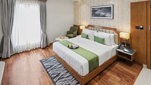Habitación de hotel con una cama grande, una mesita de noche, una silla, un escritorio, un teléfono y una obra de arte colgada en la pared.