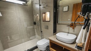Un baño moderno con ducha de vidrio, lavamanos blanco y retrete.