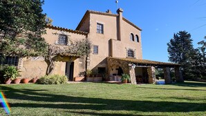 Edifici tradicional amb façana de pedra, teulada a dues aigües i zona de pati coberta.