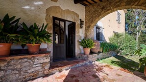 Edifici de pedra amb entrada enrajolada i plantes en testos.