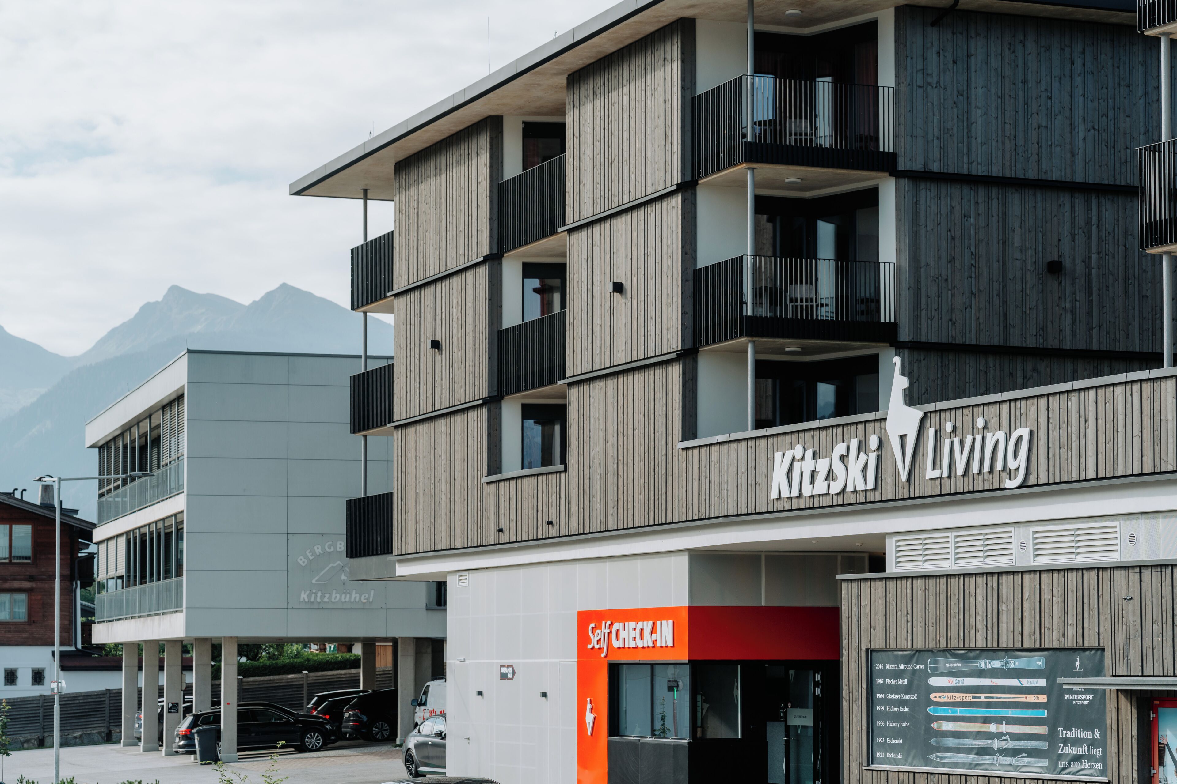 Un hôtel à plusieurs étages doté de balcons, d’un espace d’enregistrement automatisé et d’une enseigne indiquant « Kitzski Living ».