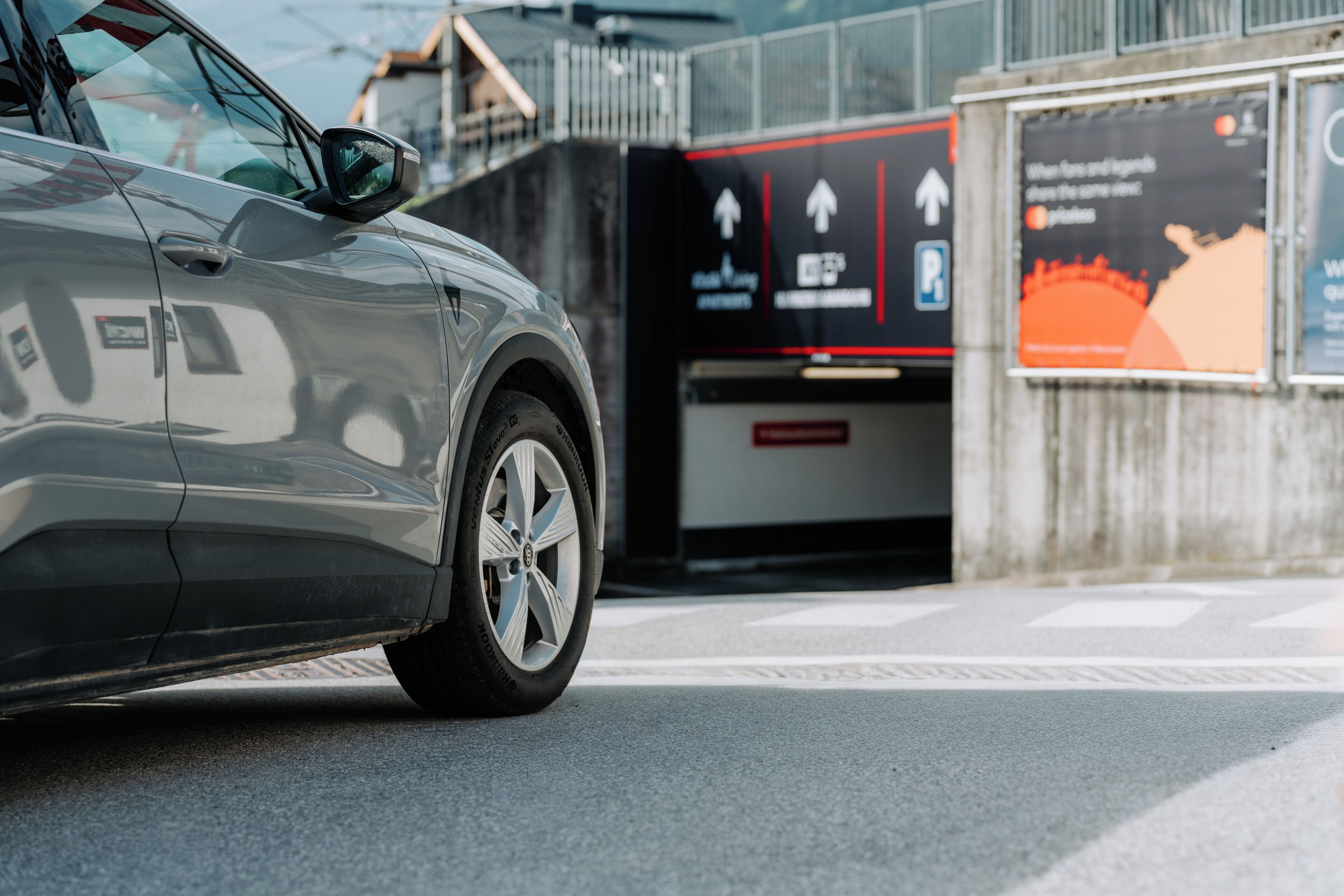 A car parked in front of a building with a sign indicating parking availability and directional arrows.