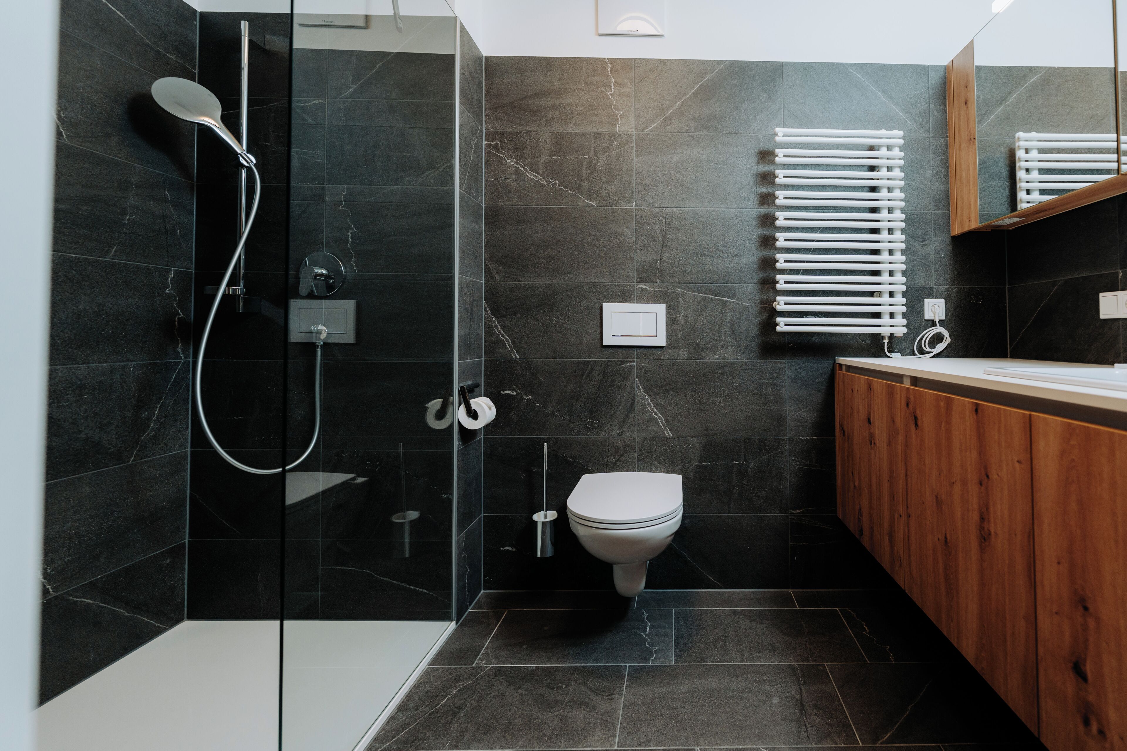 A modern bathroom with a glass-enclosed shower, a toilet, and a wooden vanity.