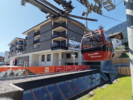 A modern building with balconies, a ski lift, and a sign for 'Hansi Hinterseer.'