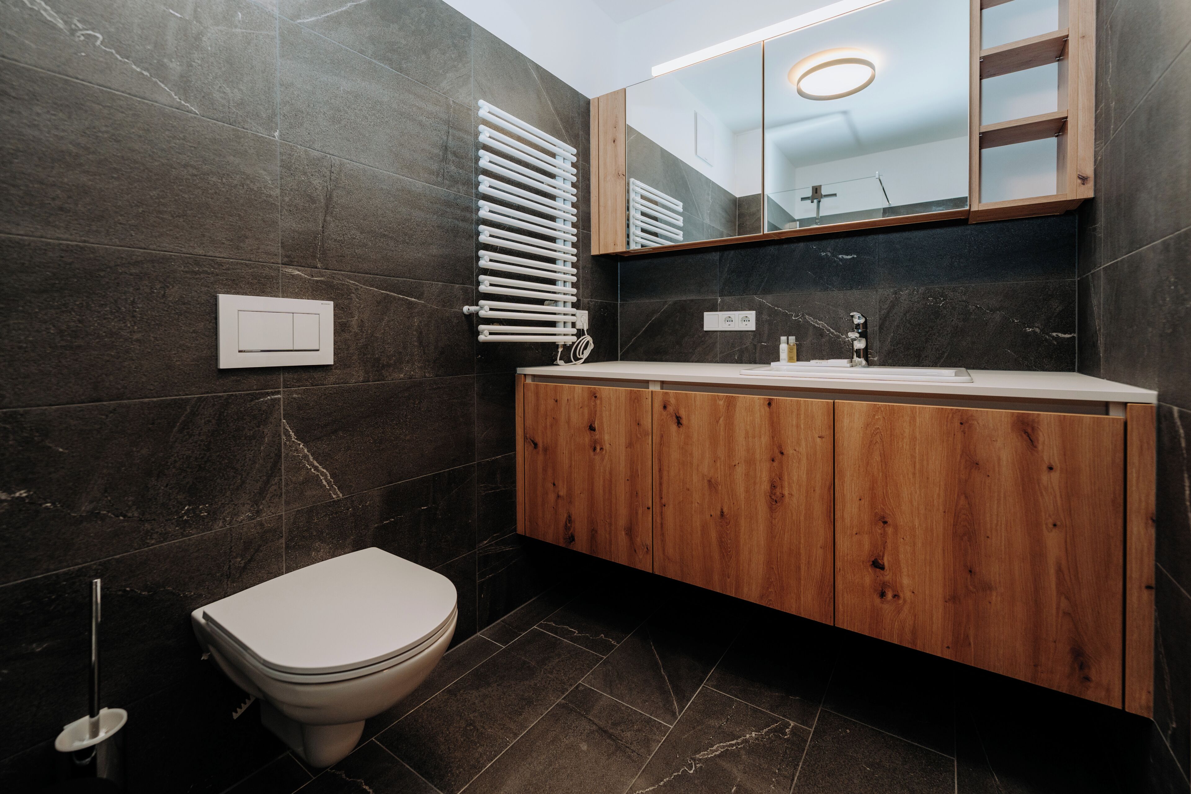Une salle de bain moderne avec des toilettes, un meuble-lavabo en bois et un miroir.