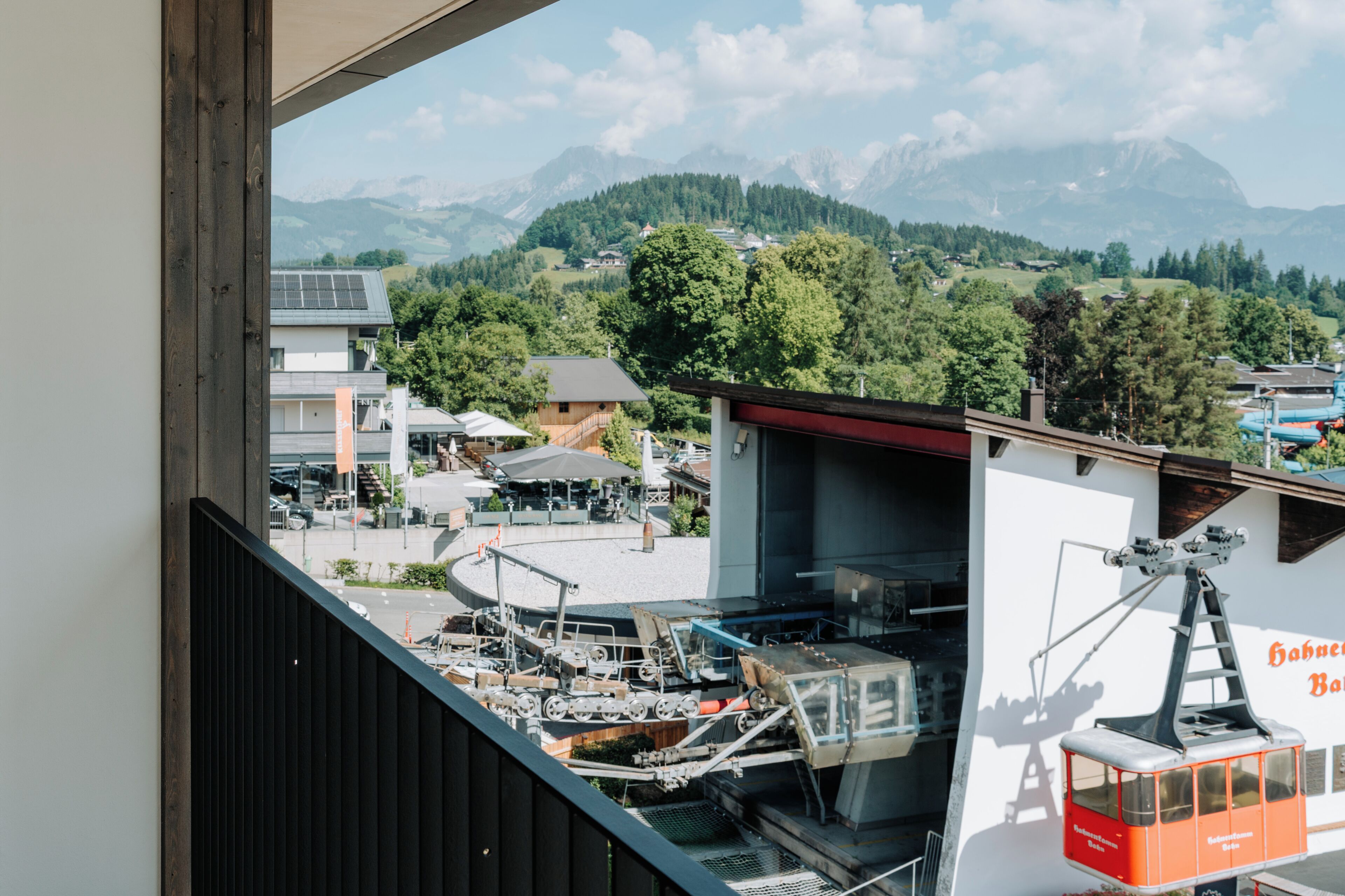 A view from a balcony overlooking a mountainous landscape with a cable car system and buildings in the foreground.
