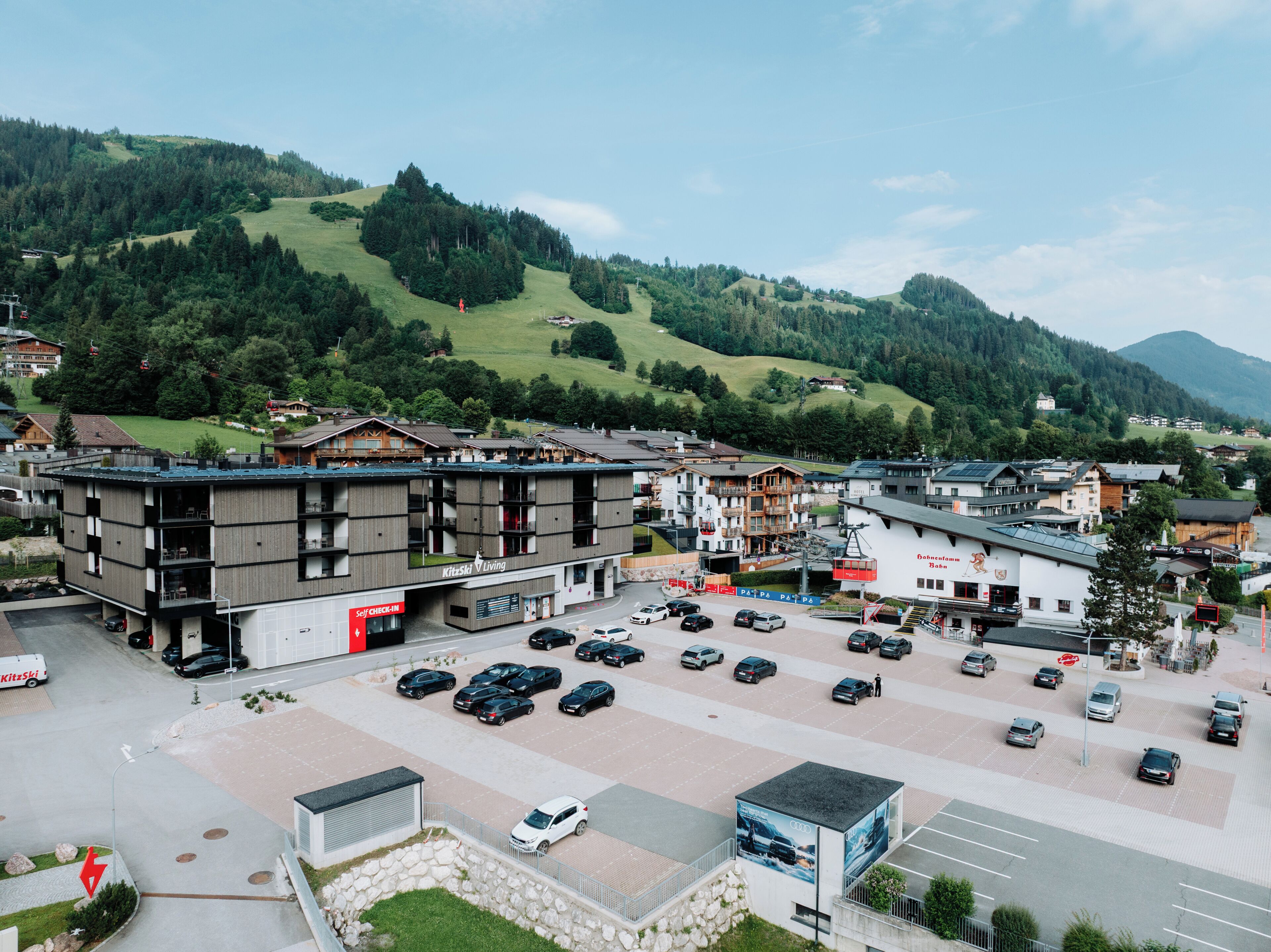 A hotel with a modern design, a parking lot, and a view of the surrounding hills.