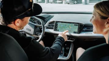 Ein Auto Innenraum mit Navigationssystem, Lenkrad und Vordersitz.