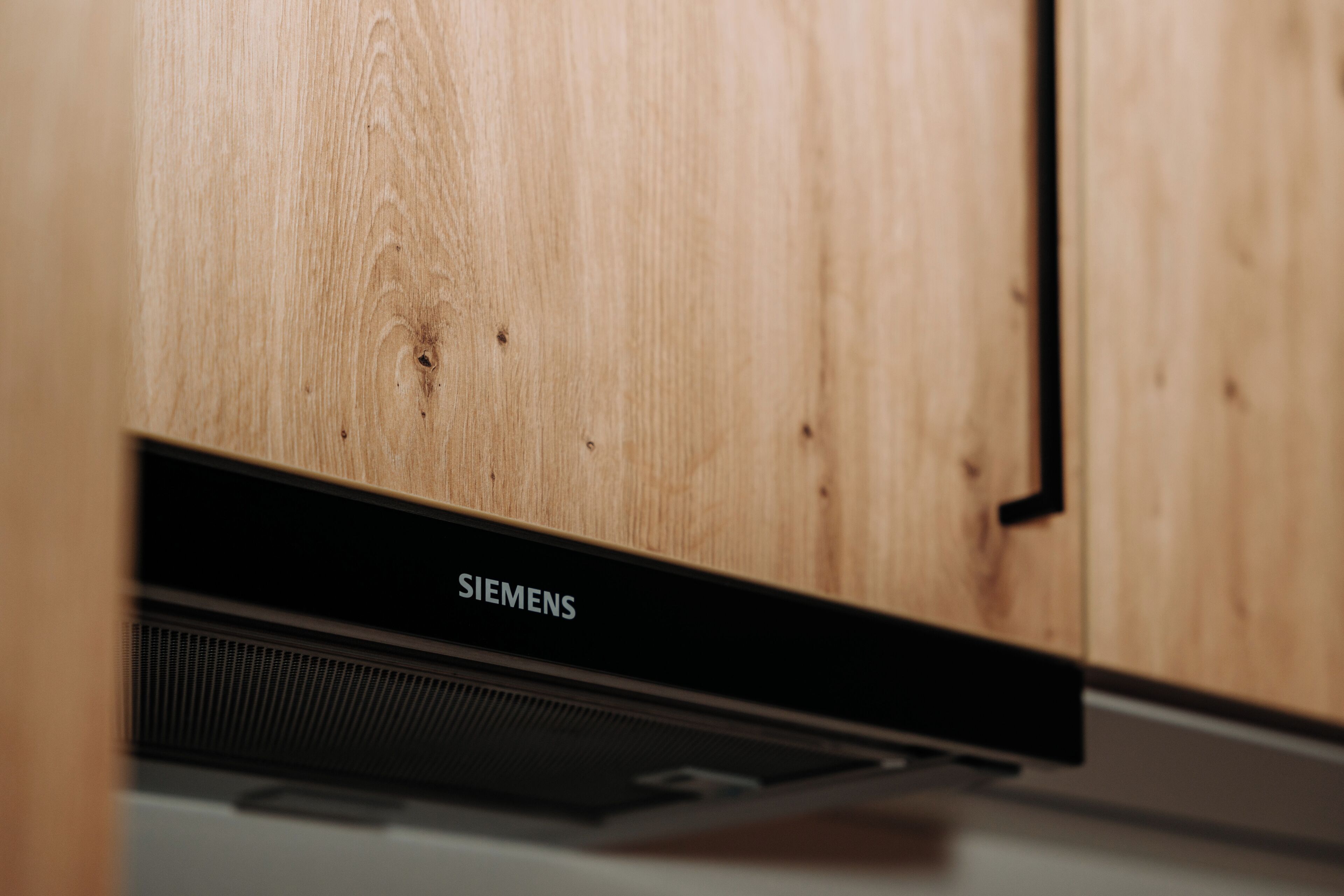 Una cocina con un armario de madera y un electrodoméstico Siemens.