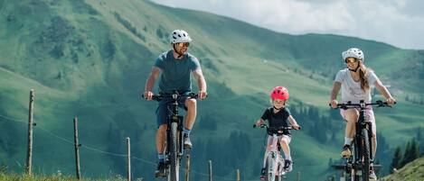 Tres personas montando en bicicleta por una carretera con un paisaje montañoso al fondo.