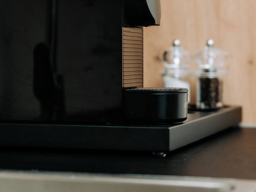 A coffee machine on a countertop with a wooden background.