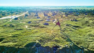 Vista aérea de un paisaje rural con casas dispersas, una estructura prominente en forma de estrella roja y una carretera.