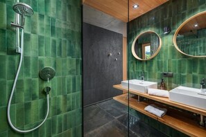 Une salle de bain moderne avec des carreaux verts, une douche, deux lavabos et un miroir.