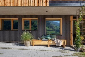 Un bâtiment moderne avec une façade en bois, de grandes fenêtres et un banc à l’extérieur.