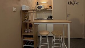 A compact kitchen with a microwave, coffee maker, and a small countertop. There are two stools and a cabinet below the counter. - CosyWellington-Studio near Arras station and center (Achicourt)