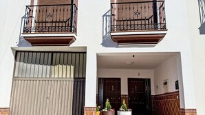 Un edificio a due piani con un balcone, un ingresso con cancello e piante in vaso.
