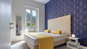 Una camera da letto moderna con un ampio letto, un comodino e una finestra vista su piante.