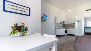 Una cucina moderna con mobili bianchi, una lavatrice e un'area pranzo con tavolo e sedie bianche.