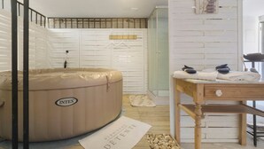 A room with a hot tub, a wooden table with towels, a wooden bench, and a wall-mounted towel rack. - Holiday Home “La Perle Rosée” with Private Terrace, and Wi-Fi (Azerat)