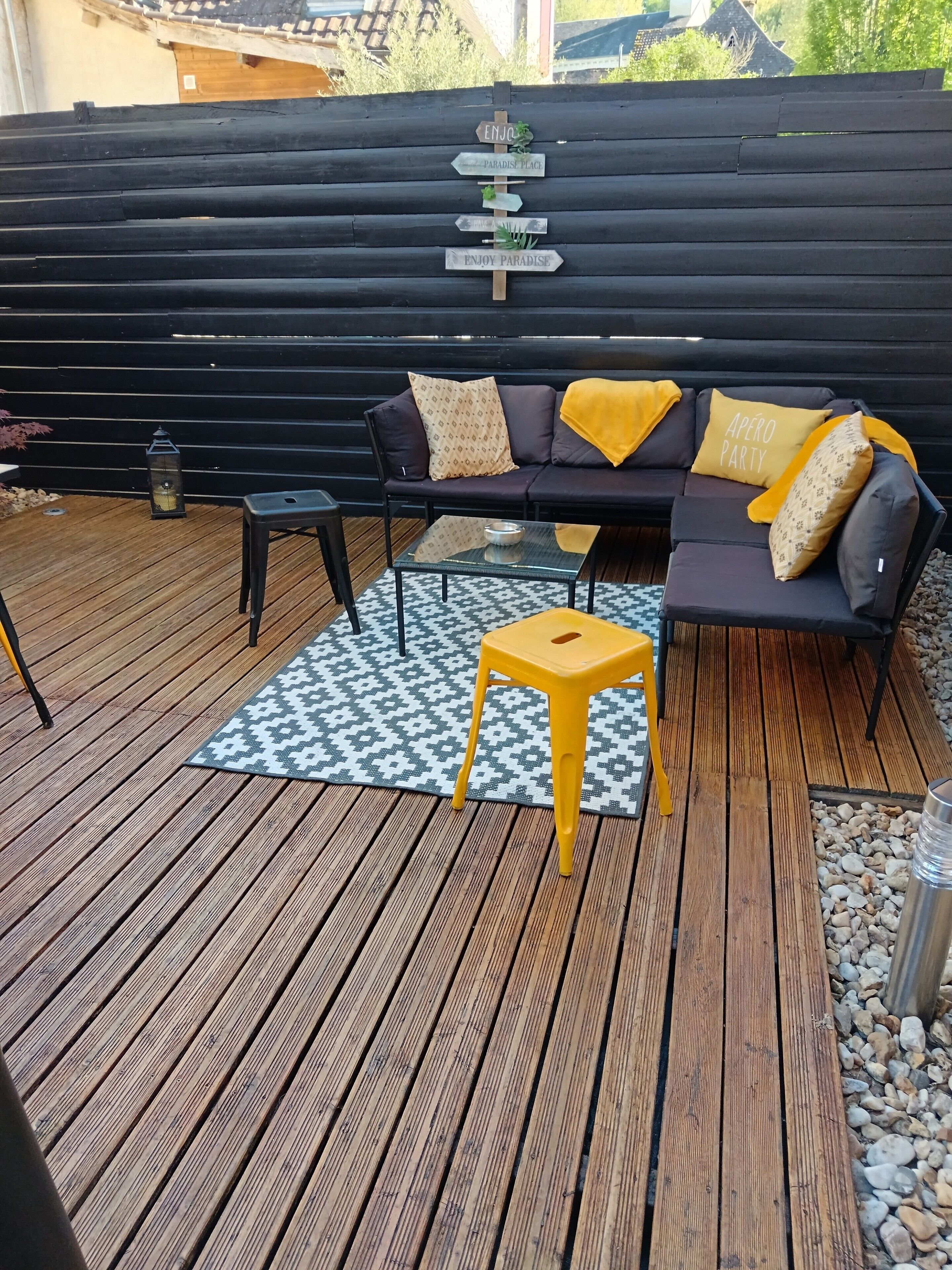 A wooden deck with a sofa, a small table, and a lantern.