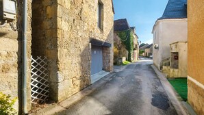 A narrow street with stone buildings, a metal fence, and a clear sky. - Holiday Home “La Perle Rosée” with Private Terrace, and Wi-Fi (Azerat)