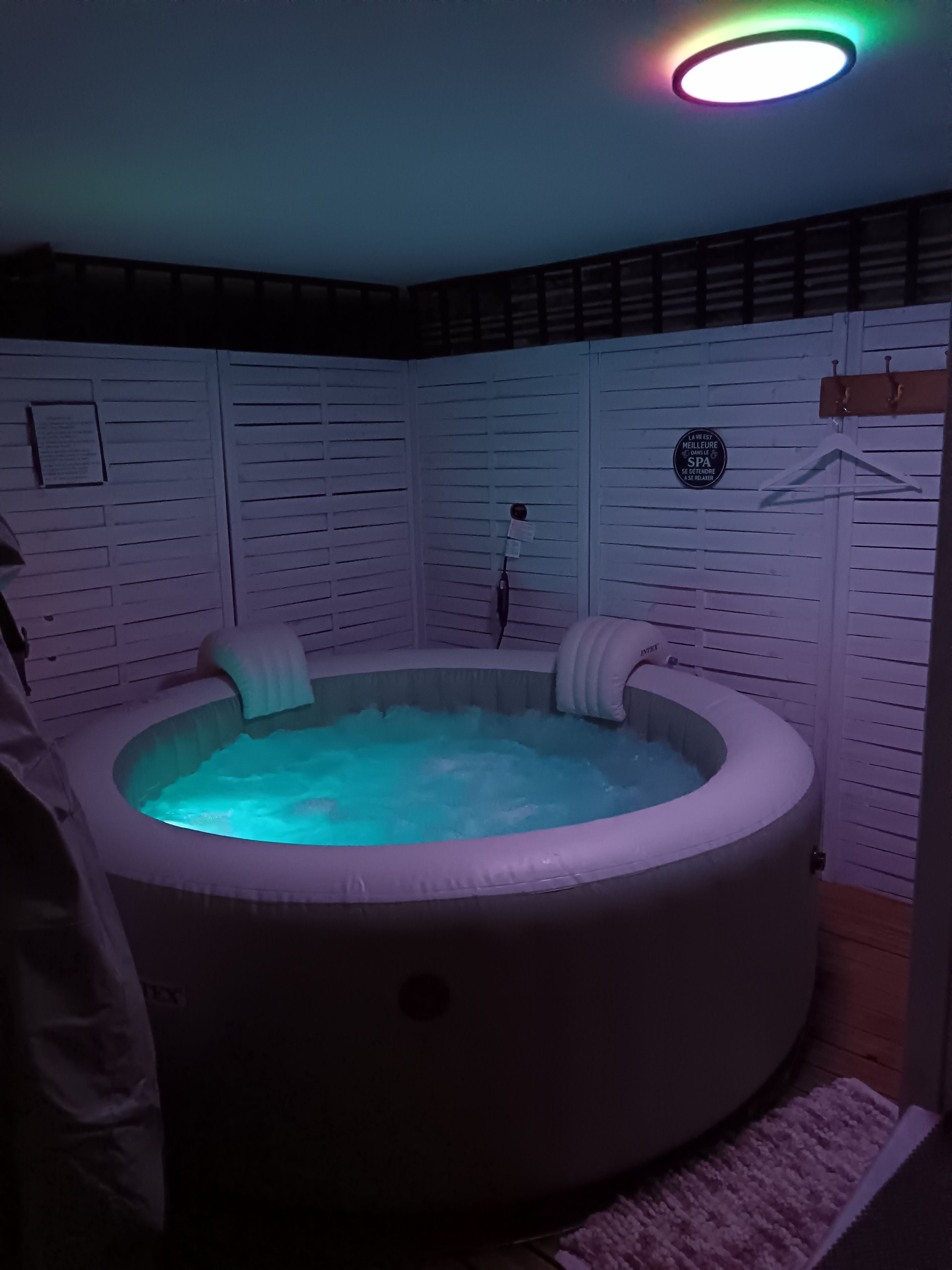 A hot tub with a light fixture above it, surrounded by white paneling.