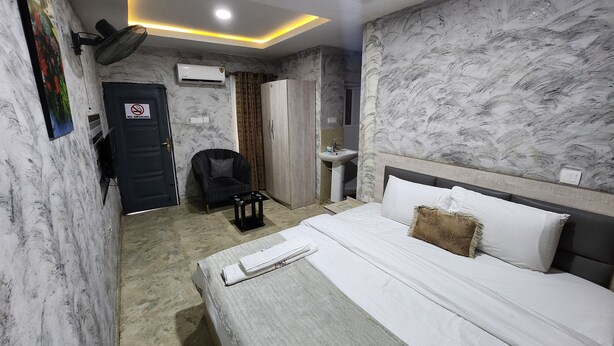 Una habitación de hotel con cama, una silla, un escritorio, un armario y baño.
