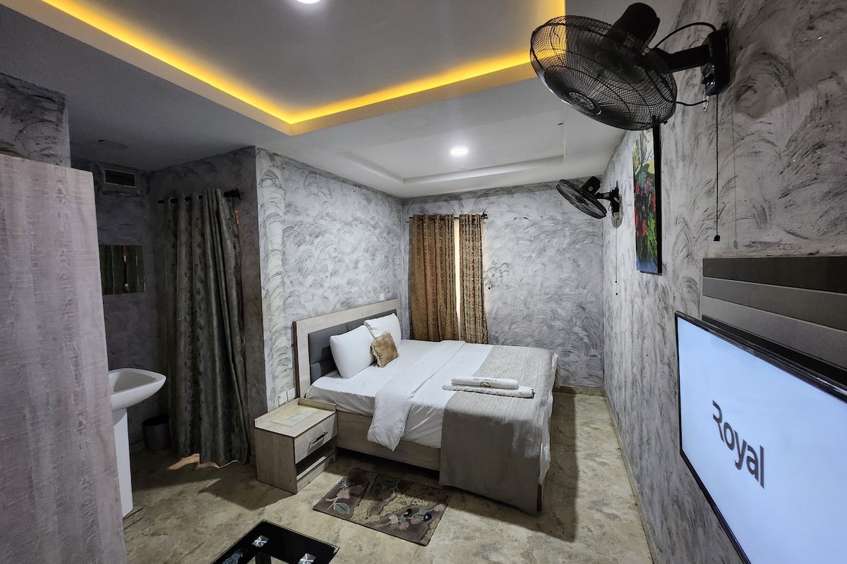 A modern bedroom with a bed, bedside table, and a wall-mounted TV.