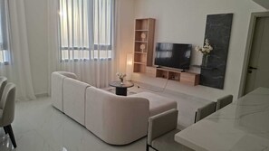 Una sala moderna con un sofá modular, un televisor de pantalla plana, una mesa de comedor y una decoración minimalista.
