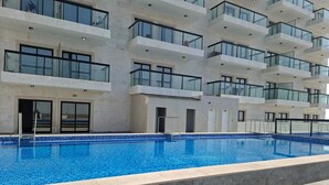 A modern building with a swimming pool, large windows, and balconies. - Close to Jabel Ali free zone easy access to Dubai and Abu Dhabi (Dubai)