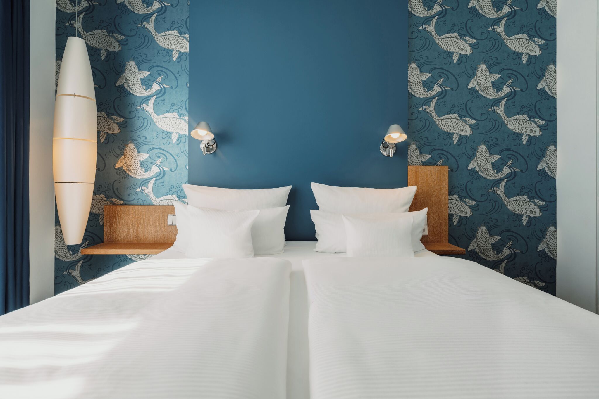 Een hotelkamer met een groot bed, twee wandlampen en een surfboard decoratie.