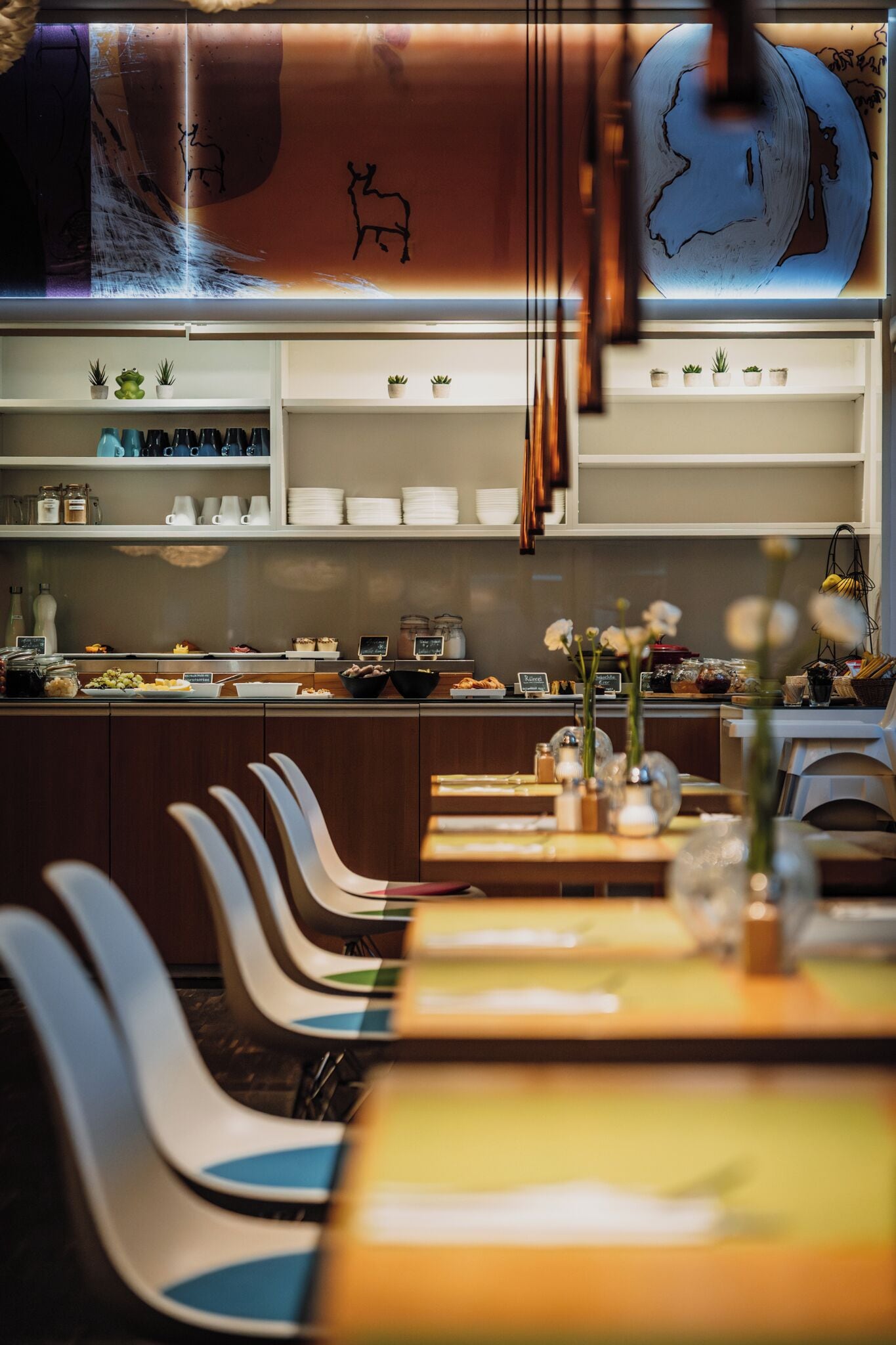 A restaurant with a counter, chairs, and a decorative wall.