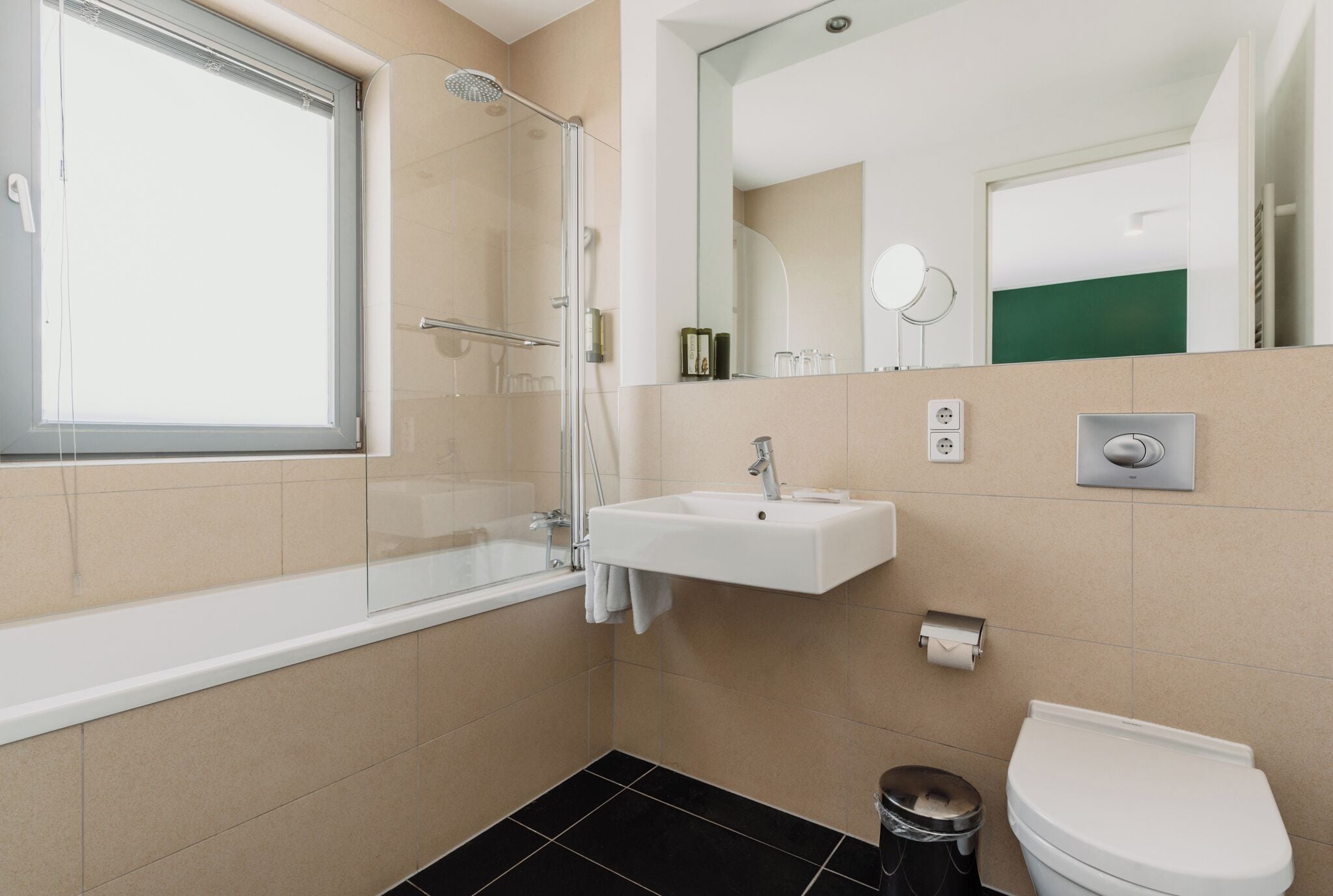 A modern bathroom with a glass shower enclosure, a white sink, a toilet, and a mirror above the sink.