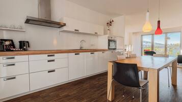 A modern kitchen with white cabinets, a wooden countertop, and a dining area with a table and chairs.