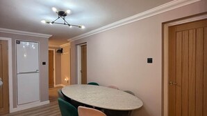 Un espace repas comprenant une table ronde et des chaises, un luminaire suspendu au plafond et un revêtement de sol en bois.