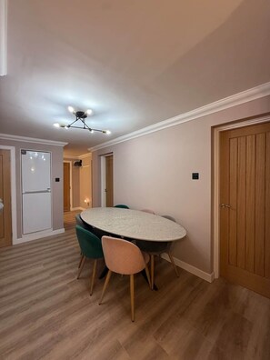 A dining area with a round table and chairs, a ceiling light fixture, and wooden flooring. - Luxury 3 Bed Apartment Fort William (Fort William)