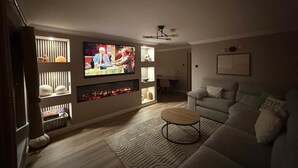 Un salon avec un téléviseur à écran plat fixé au mur, une cheminée, un canapé et une table basse.