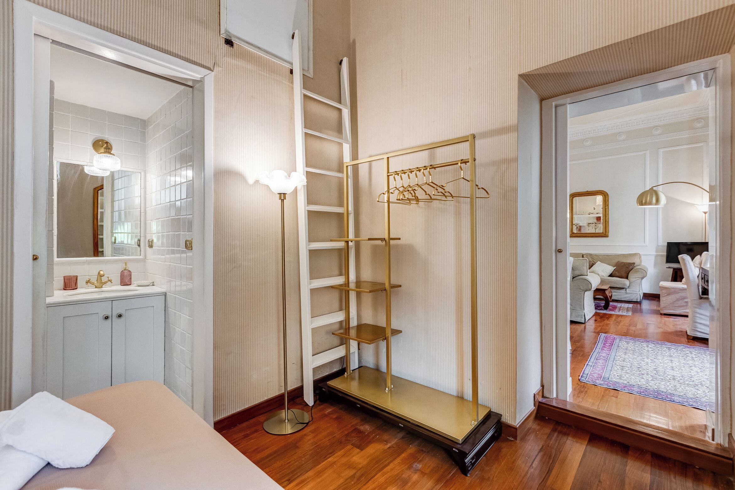 Een slaapkamer met een bed, een kledingkast, een spiegel en een ophangrek.