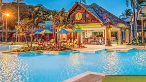 Un resort con piscina, sillones de descanso y zona de bar.