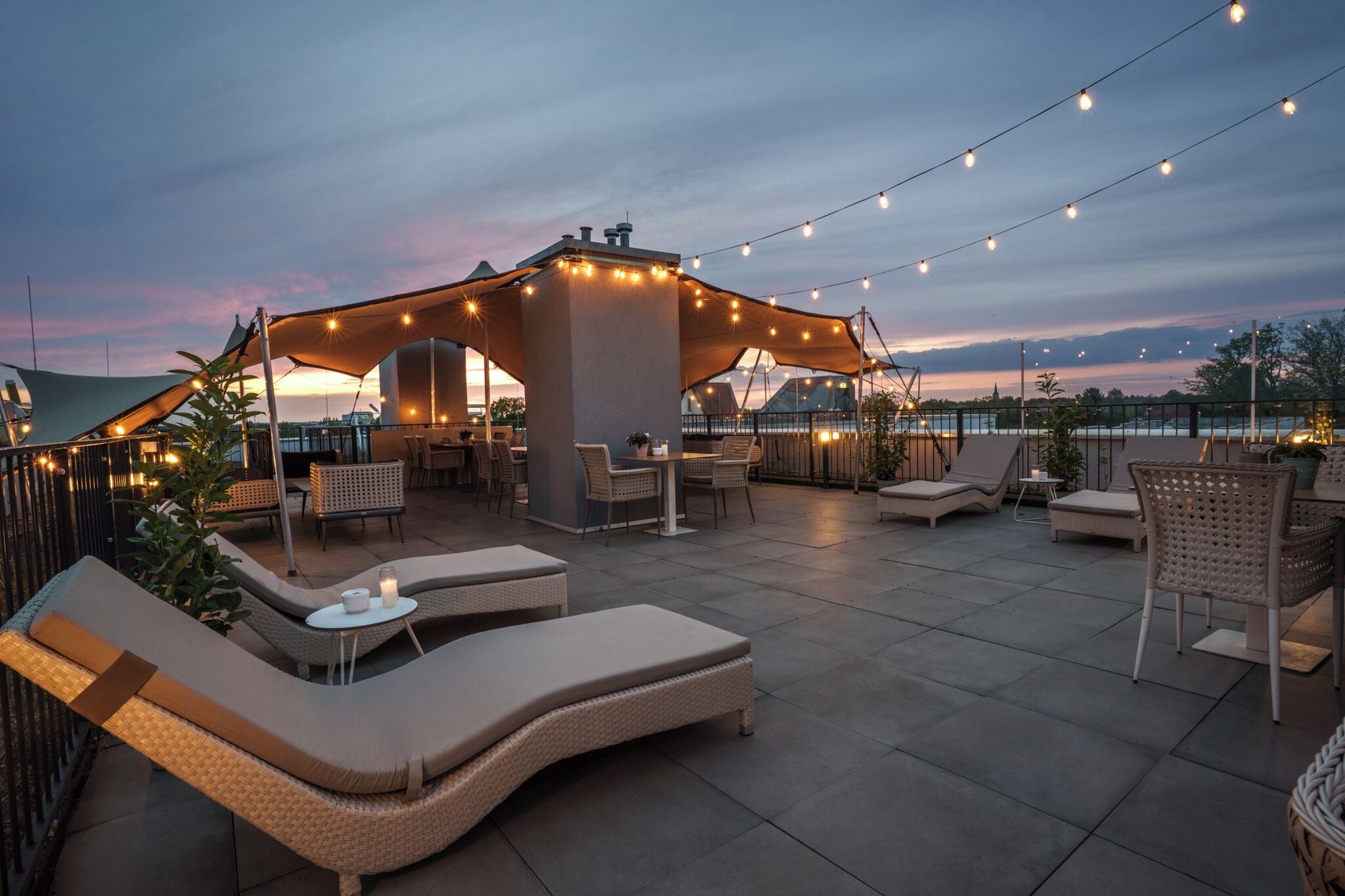 An outdoor patio area with lounge chairs, a table, and string lights.