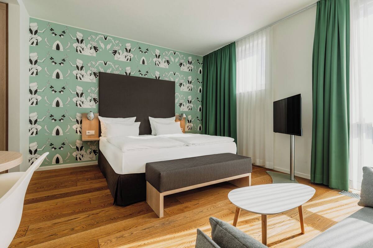 Una habitación de hotel con cama, televisión, escritorio y silla.
