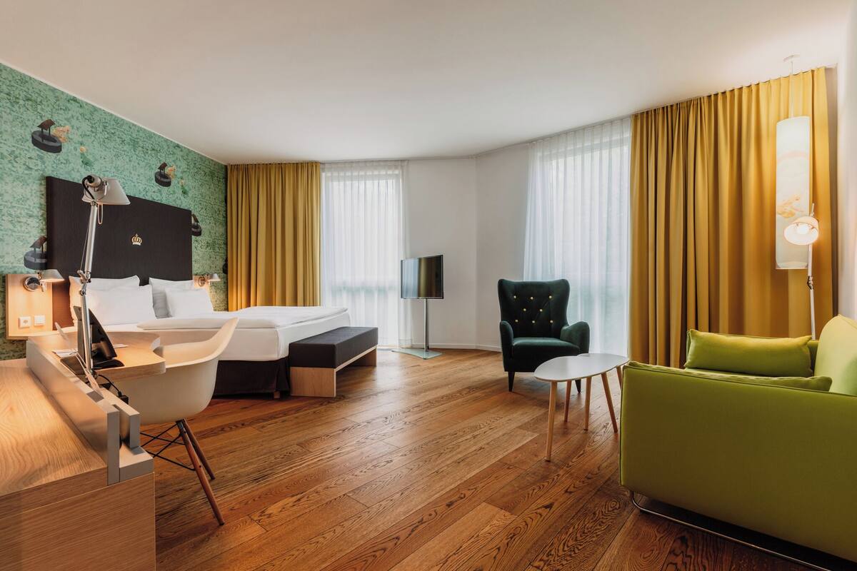 Habitación de hotel con cama, escritorio, silla, sofá y televisor.