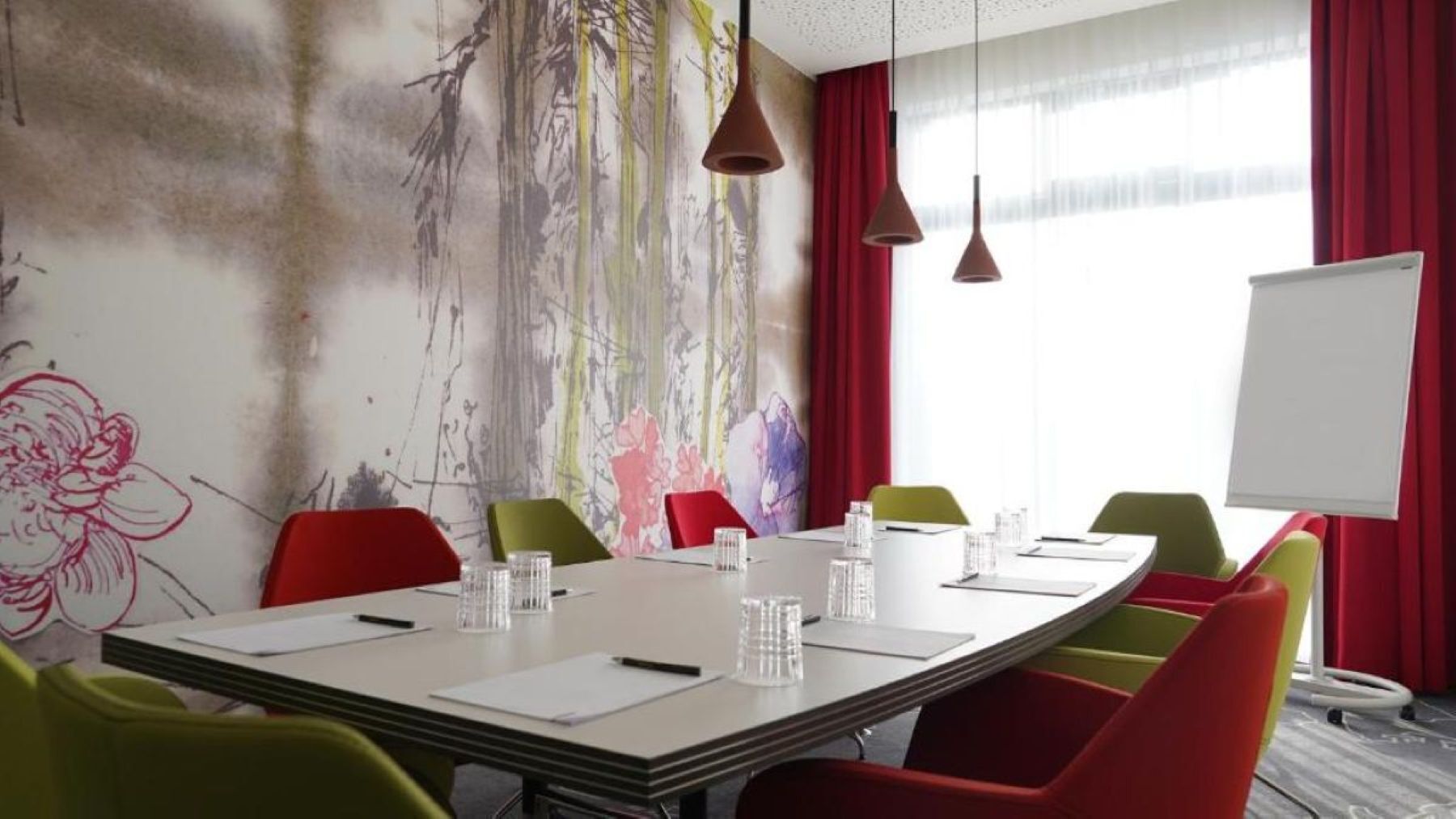 A conference room with a large table, colorful chairs, and a whiteboard.