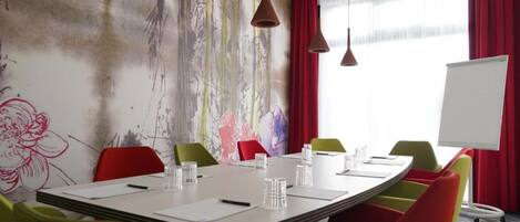 A conference room with a large table, colorful chairs, and a whiteboard.