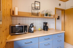 A kitchenette with a microwave, coffee maker, and a shelf with a plant and a framed picture. - Apartment Gartenblick – Spacious Retreat with Garden View in Korbach (Korbach)