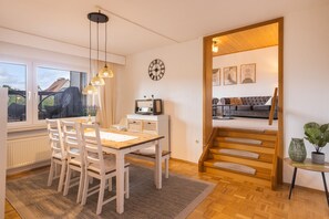 Un salon moderne comprenant un coin repas, un escalier et une vue sur l’extérieur.