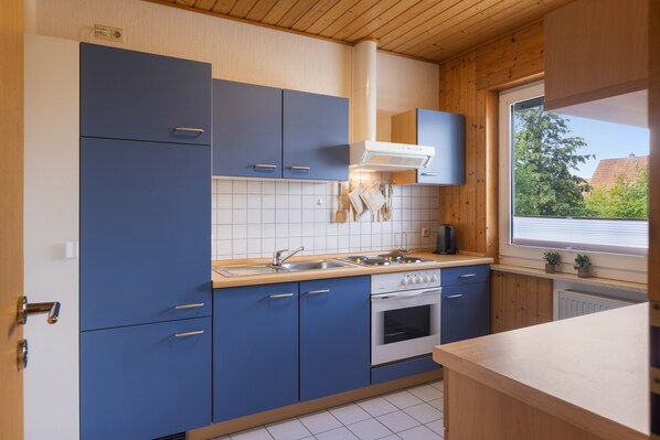 Una cocina moderna con armarios azules, una estufa blanca y una ventana con vistas a zonas verdes.