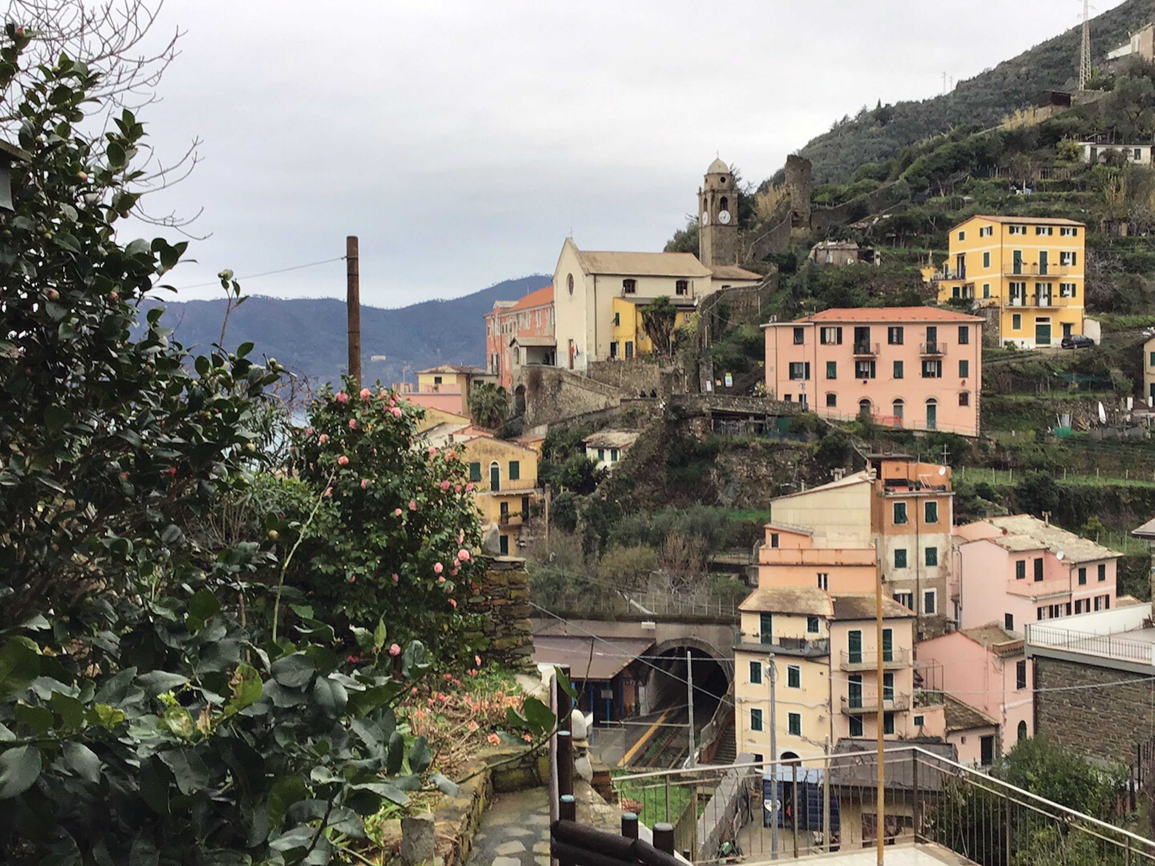A hillside village with colorful buildings, a church, and a railway track.