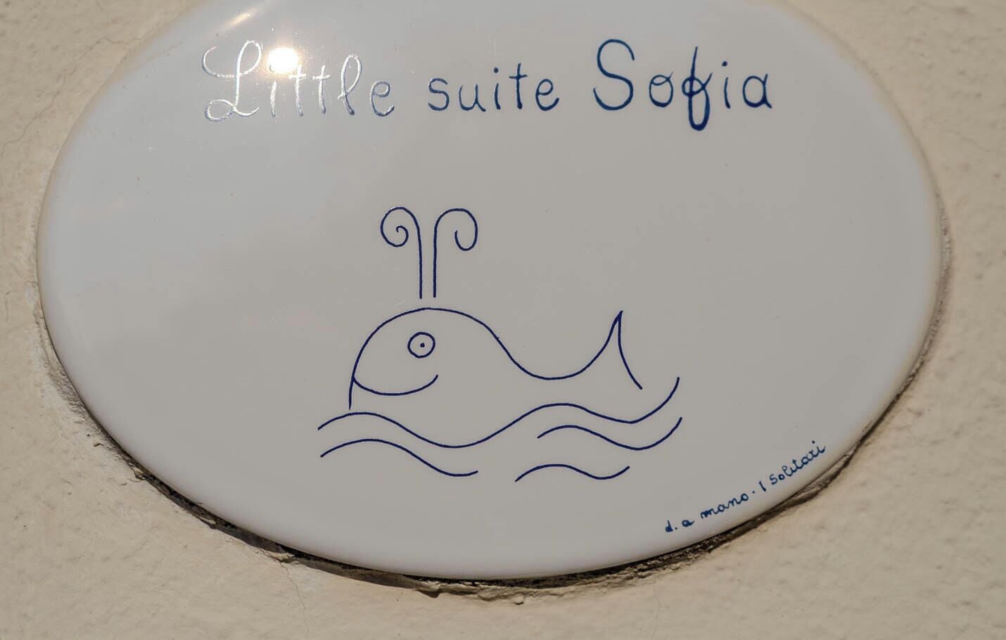 A sign with a drawing of a whale and the text 'Little suite Sofia' and 'd. a marina - I Soltari'.