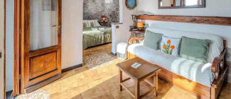 A cozy room with a wooden door, a sofa with pillows, a small table, and a stone wall.